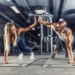 Sport couple doing plank exercise workout in fitness centrum. Man and woman practicing plank in the gym